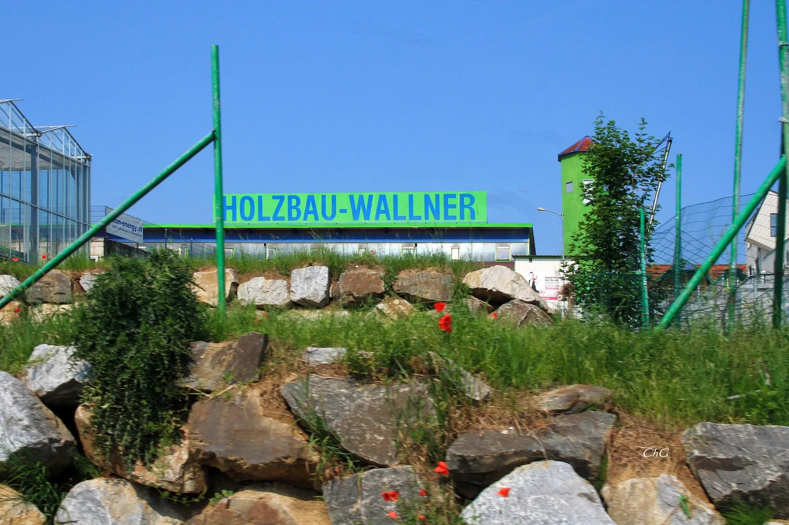 Firmengelände in Asperhofen mit dem grünen Schild Holzbau-Wallner über einer Steinmauer