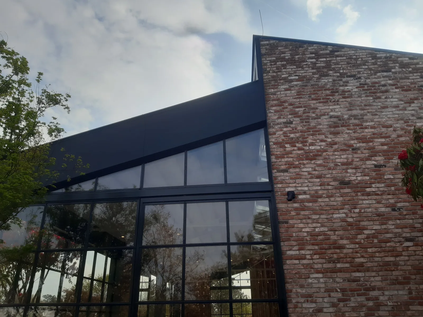 Ziegelbau mit großer Glasfront und dunklem Blechdach